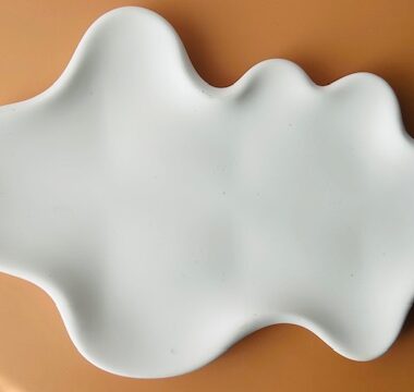 Irregular-shaped decorative tray in white, made from cement or gypsum, placed on a light brown surface &ndash; part of Soy Decor by SoyandGlow.